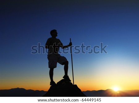 Man at the top of a mountain range at sunrise