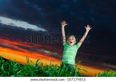 Photo of young boy raising hands in outside