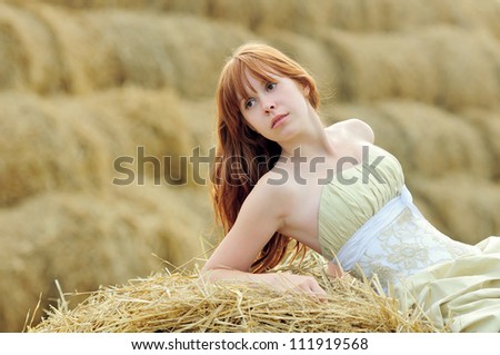 bride in wedding dress in a field with haystack