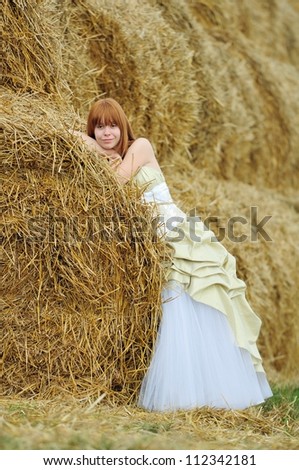 bride in wedding dress in a field with haystack
