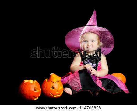 Halloween little girl witch with a carved pumpkin over black background with smoke