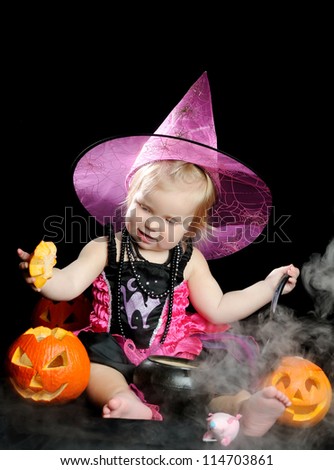 Halloween little girl  witch with a carved pumpkin over black background with smoke