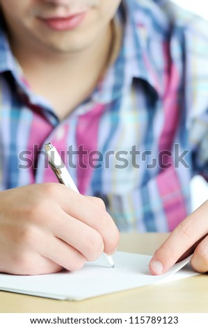 Close-up of young businessman writing on document