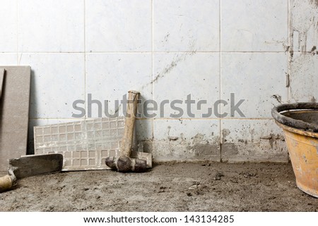 Section of the floor of a house under renovation showing the concrete subfloor and some tools