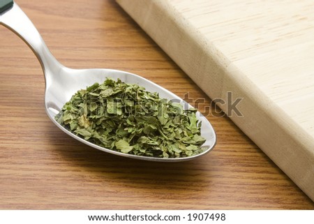Spoonful of chopped coriander leaves besides a chopping board