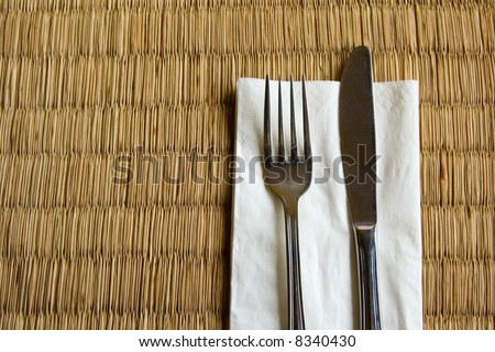 Fork and knife on a dried grass mat commonly found in an Asian restaurant