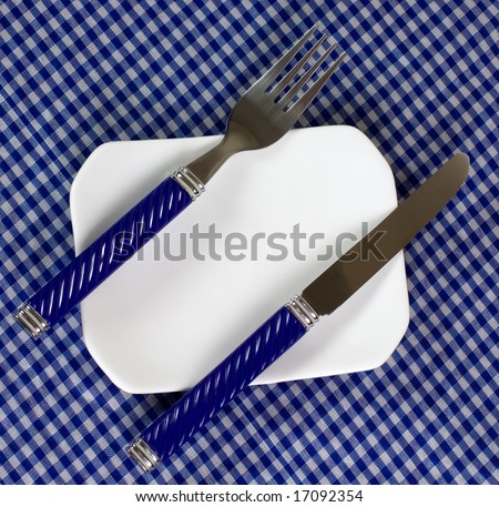 Top view of an empty plate with fork and knife on a dining table
