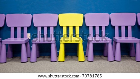 Children\'s chairs - A yellow colored one in the middle of several purple colored chairs for kids