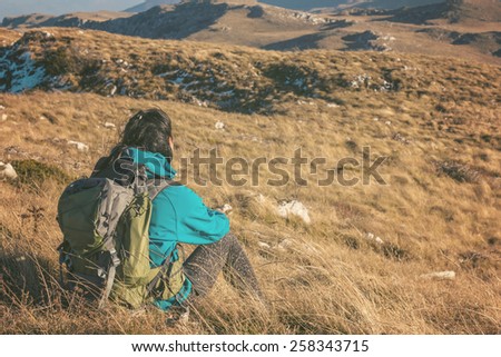 Woman hiking in beautiful nature, back light by morning sunlight rays, recreation and healthy lifestyle outdoors in wild. Hiker backpacker sitting on mountain top.