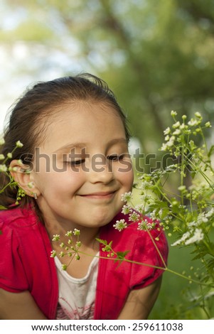 Cute little girl smell flower in nature