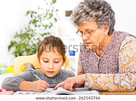 Grandmother and daughter writing and learning homework at domestic room