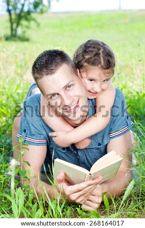 Nice day in nature, father and daughter relaxing reading book in nature