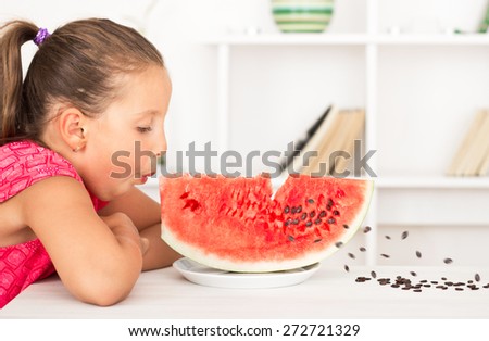 Little girl cleaning seeds from watermelon by easy way