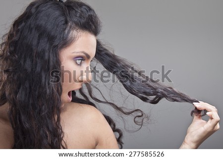 Young girl looking in damaged hair with strong expression