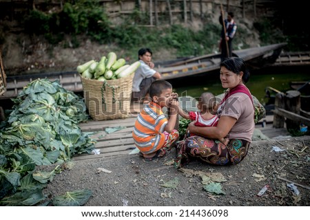 INLE LAKE, MYANMAR (BURMA) - 22 April 2014: Local Burmese Intha woman cut and sell vegetable on a traditional open market. Local markets serves most common shopping needs Inle Lake people.
