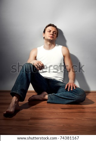 Portrait of one sad young man sitting on the floor