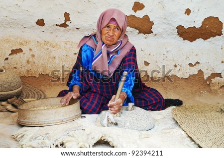 SAHARA DESERT, TUNISIA - AUGUST 30: Old woman grinds grains for flour on August 30, 2011 near Sahara Desert, Tunisia