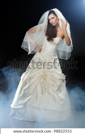 Slim beautiful woman wearing luxurious wedding dress over black studio background