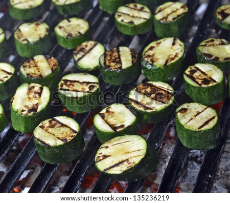 Grilled zucchini cooking on an open flame grill