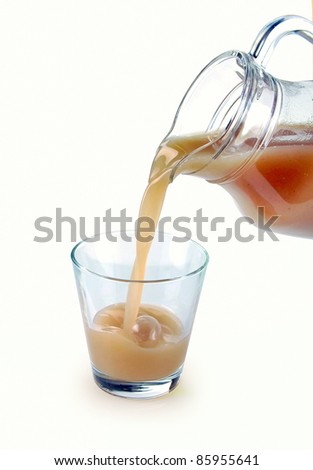 pear juice is poured from a jug into a glass