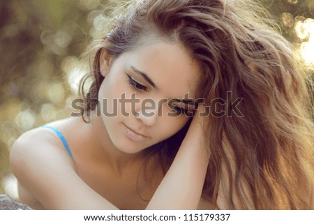 Young woman with curly hairs outdoors portrait. Soft sunny colors.