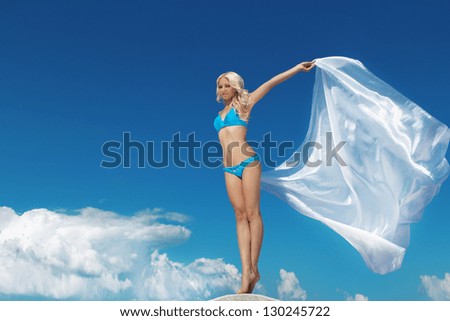 Beautiful woman feeling free against blue sky with blowing fabric. Travel and Vacation. Freedom Concept