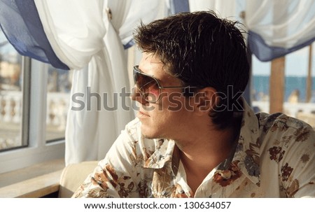 Elegant young handsome man in sunglasses looking at window