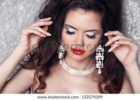 Fashion Portrait of beautiful woman with perfect make up over party lights. Jewelry and Beauty.