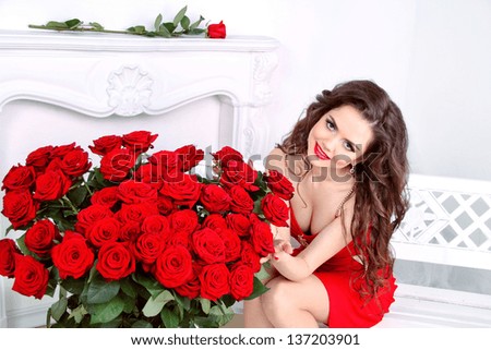 Beautiful smiling woman with red roses flowers bouquet in modern interior apartment
