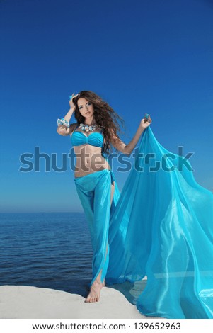Enjoyment - free sexy woman enjoying happiness. Beautiful woman in blue chiffon dress embracing over blue sky