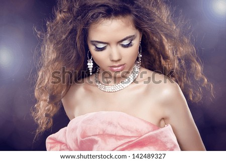 Beauty Glamour Portrait of sexy woman with long curly hair and fashion makeup over party lights.