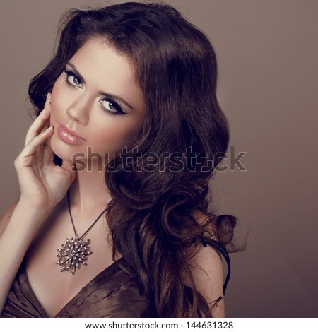 Portrait of Beautiful woman with curly hair and evening make-up. Jewelry and Beauty. Fashion girl photo