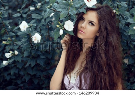 Beautiful Woman with Curly Long Hair. Outdoors Portrait on garden background, summer nature.