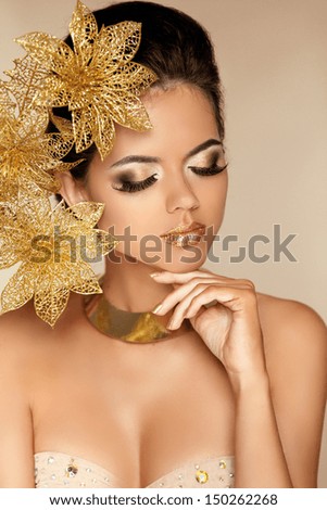Beautiful Girl With Golden Flowers. Beauty Model Woman Face. Perfect Skin. Professional Make-Up. Makeup. Fashion Art