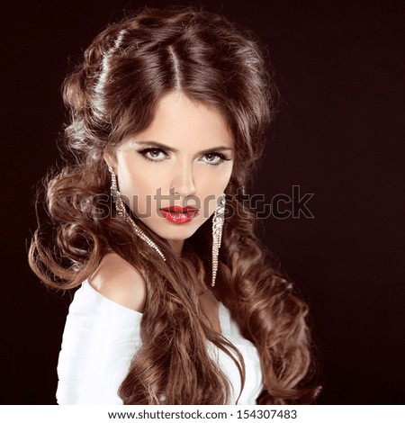 Hairstyle. Beautiful Girl Portrait. Beauty Woman with brown curly long hair styling over dark. Red Lips