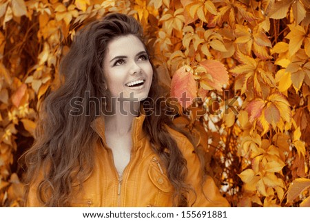 Enjoyment. Young happy smiling brunette woman over autumn leaves, yellow maple park background