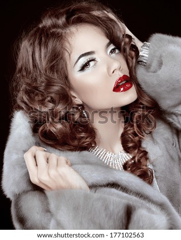 Glamour Fashion Woman Portrait. Makeup. Wavy hair. Hot sexy lips. Winter girl isolated on black background