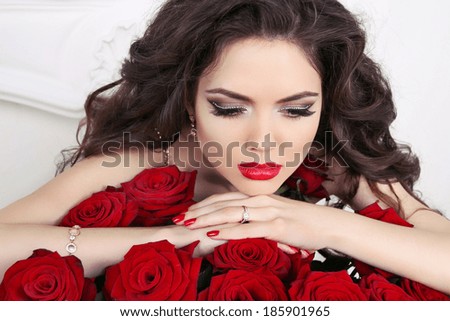 Beautiful brunette woman with red roses bouquet, valentines day. Red lips and manicured nails.