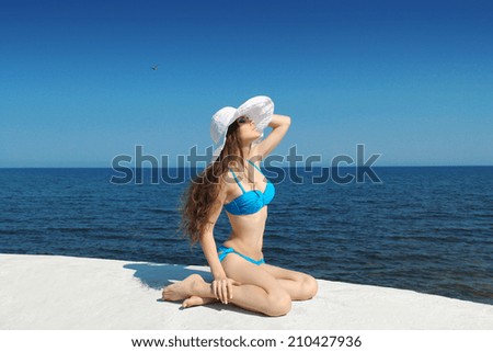 Sunbathing girl. Enjoyment. Slim bikini model woman in bikini over blue sky, summertime outdoors portrait. Brunette female.