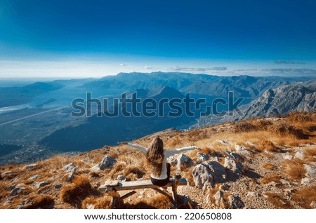 Young enjoying woman with raised hands on the top of a mountain, cheering elated and blissful