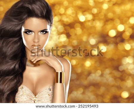 Fashion girl with Long shiny wavy hair and beauty makeup, luxury gold jewelry isolated over  golden holiday bokeh lights background.