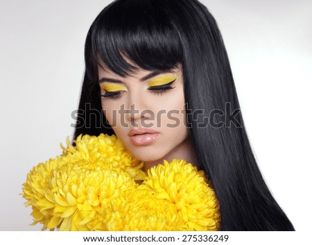 Makeup. Beautiful model brunette with long straight glossy hair and Yellow Eyeshadow with eyeliner with bright flowers.