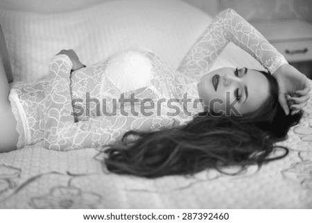 Sensual brunette woman in sensual underwear lying on bed, passionate person. Black and white portrait.
