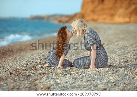 Mother kissing her daughter on the beach. outdoor family portrait. two same look person.