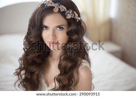 Hairstyle. Beautiful brunette bride girl with long healthy wavy hair styling posing in modern interior.