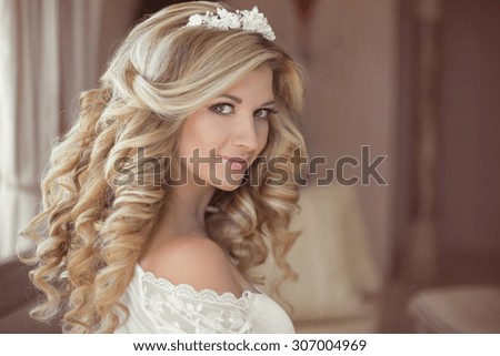 Healthy hair. Beautiful smiling girl bride with long blonde curly hairstyle and bridal makeup. Wedding indoor portrait.