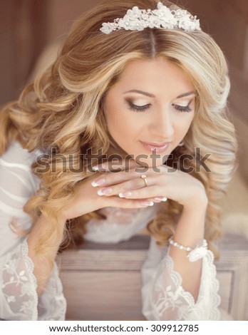 Makeup. Hair. Beautiful smiling girl bride with long blonde curly hairstyle and bridal makeup. Wedding indoor portrait.