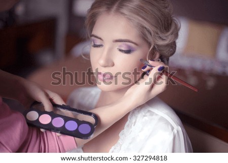 Beautiful bride girl with  wedding makeup and hairstyle. Stylist makes make-up bride on wedding day. portrait of young woman at morning.