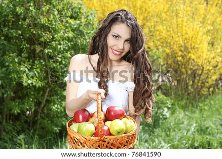 Girl in white dress presents basket of apples