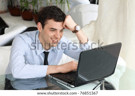 Smiling men think and work at the laptop